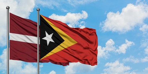 Latvia and East Timor flag waving in the wind against white cloudy blue sky together. Diplomacy concept, international relations.