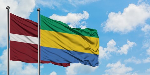 Latvia and Gabon flag waving in the wind against white cloudy blue sky together. Diplomacy concept, international relations.