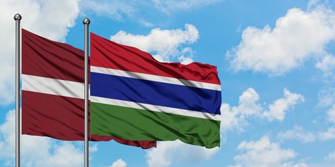 Latvia and Gambia flag waving in the wind against white cloudy blue sky together. Diplomacy...