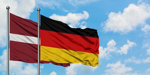 Latvia and Germany flag waving in the wind against white cloudy blue sky together. Diplomacy concept, international relations.