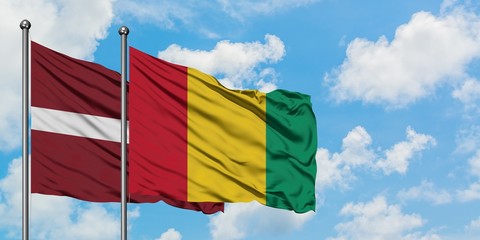 Latvia and Guinea flag waving in the wind against white cloudy blue sky together. Diplomacy concept, international relations.