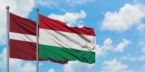 Latvia and Hungary flag waving in the wind against white cloudy blue sky together. Diplomacy concept, international relations.
