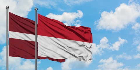 Latvia and Indonesia flag waving in the wind against white cloudy blue sky together. Diplomacy concept, international relations.