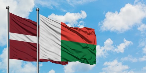 Latvia and Madagascar flag waving in the wind against white cloudy blue sky together. Diplomacy concept, international relations.