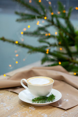 Delicious cappucino coffee cup . fireflies and spruce branches.