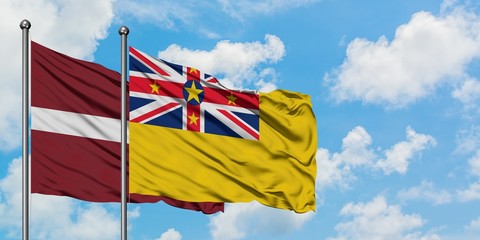 Latvia and Niue flag waving in the wind against white cloudy blue sky together. Diplomacy concept, international relations.