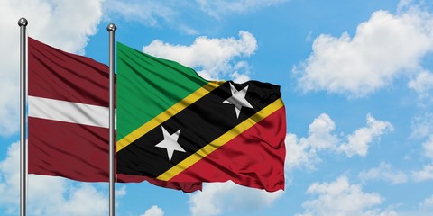 Latvia and Saint Kitts And Nevis flag waving in the wind against white cloudy blue sky together. Diplomacy concept, international relations.
