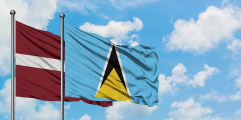 Latvia and Saint Lucia flag waving in the wind against white cloudy blue sky together. Diplomacy concept, international relations.