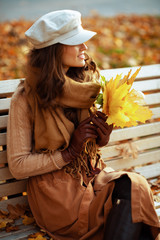 smiling young woman with yellow leaves looking into distance