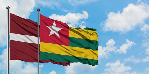 Latvia and Togo flag waving in the wind against white cloudy blue sky together. Diplomacy concept, international relations.