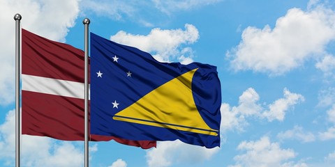 Latvia and Tokelau flag waving in the wind against white cloudy blue sky together. Diplomacy concept, international relations.