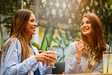 Two female friends talking and having fun at a coffee shop