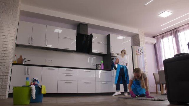 Time lapse of cleaning service work, cleaning ladies mopping, vacuuming, wiping, dusting all around kitchen area in house. Professional cleaners providing wide range of home cleaning services