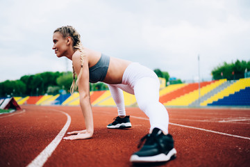 Fototapeta premium Female athlete stretching legs on racetrack