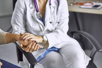 Woman doctor calms patient and holds hand