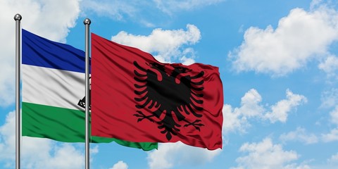 Lesotho and Albania flag waving in the wind against white cloudy blue sky together. Diplomacy concept, international relations.