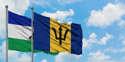 Lesotho and Barbados flag waving in the wind against white cloudy blue sky together. Diplomacy concept, international relations.
