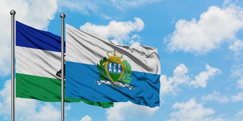 Lesotho and San Marino flag waving in the wind against white cloudy blue sky together. Diplomacy concept, international relations.