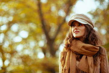trendy woman outdoors in autumn park looking into distance