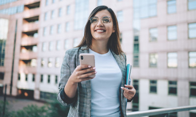 Positive Turkish female manager dressed in formal jacket looking away and smiling during online...