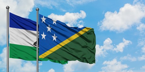 Lesotho and Solomon Islands flag waving in the wind against white cloudy blue sky together. Diplomacy concept, international relations.