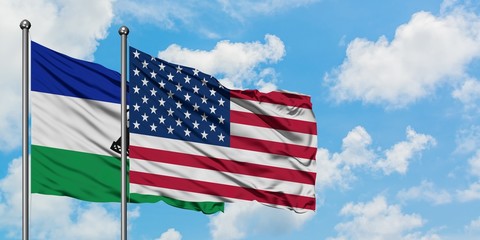 Lesotho and United States flag waving in the wind against white cloudy blue sky together. Diplomacy concept, international relations.