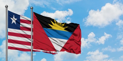 Liberia and Antigua and Barbuda flag waving in the wind against white cloudy blue sky together. Diplomacy concept, international relations.