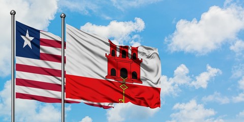 Liberia and Gibraltar flag waving in the wind against white cloudy blue sky together. Diplomacy concept, international relations.
