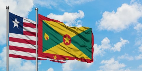 Liberia and Grenada flag waving in the wind against white cloudy blue sky together. Diplomacy concept, international relations.