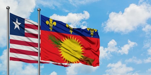 Liberia and Guadeloupe flag waving in the wind against white cloudy blue sky together. Diplomacy concept, international relations.