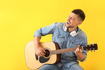 Handsome man playing guitar on color background