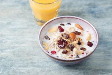 Bowl of granola with milk, nuts, raisins and cranberries. Concept for a tasty and healthy meal. Rustic wooden background. Close up.