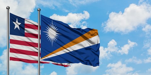 Liberia and Marshall Islands flag waving in the wind against white cloudy blue sky together. Diplomacy concept, international relations.