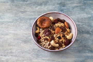 Bowl of granola with nuts, raisins and fig. Concept for a tasty and healthy meal. Rustic wooden background. Close up.
