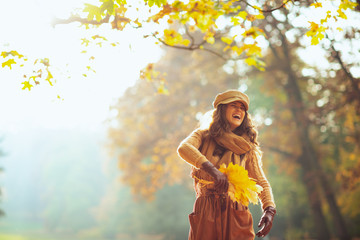 woman with yellow leaves having fun time outside in autumn park
