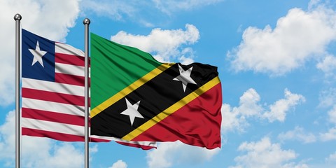 Liberia and Saint Kitts And Nevis flag waving in the wind against white cloudy blue sky together. Diplomacy concept, international relations.