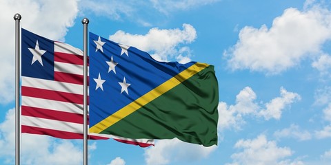 Liberia and Solomon Islands flag waving in the wind against white cloudy blue sky together. Diplomacy concept, international relations.