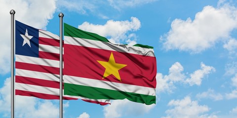 Liberia and Suriname flag waving in the wind against white cloudy blue sky together. Diplomacy concept, international relations.