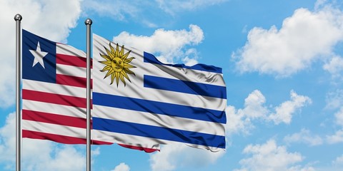 Liberia and Uruguay flag waving in the wind against white cloudy blue sky together. Diplomacy concept, international relations.