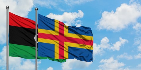 Libya and Aland Islands flag waving in the wind against white cloudy blue sky together. Diplomacy concept, international relations.