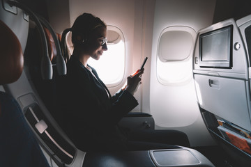 Silhouette of female person watching online video on cellular phone during business trip  enjoying...