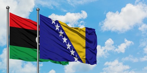Libya and Bosnia Herzegovina flag waving in the wind against white cloudy blue sky together. Diplomacy concept, international relations.