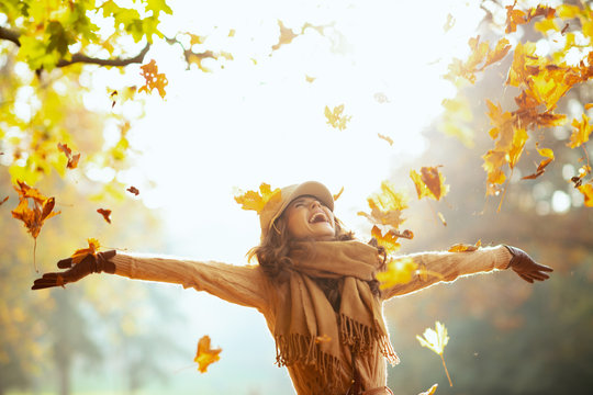 woman enjoying autumn and catching falling yellow leaves