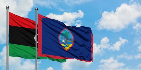 Libya and Guam flag waving in the wind against white cloudy blue sky together. Diplomacy concept, international relations.