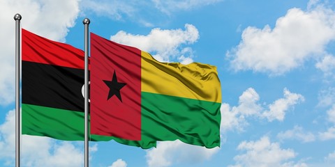 Libya and Guinea Bissau flag waving in the wind against white cloudy blue sky together. Diplomacy concept, international relations.