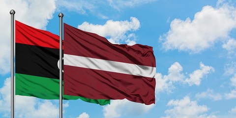 Libya and Latvia flag waving in the wind against white cloudy blue sky together. Diplomacy concept, international relations.