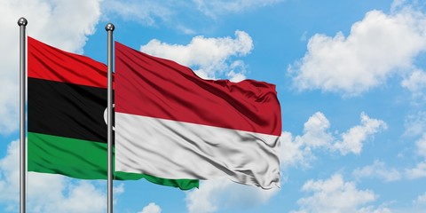 Libya and Monaco flag waving in the wind against white cloudy blue sky together. Diplomacy concept, international relations.