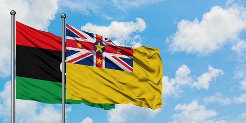 Libya and Niue flag waving in the wind against white cloudy blue sky together. Diplomacy concept, international relations.