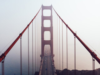 Aerial view of Golden Gate Bridge in foggy visibility during evening time, metropolitan transportation  infrastructure, birds eye view of automotive car vehicles on road of suspension construction