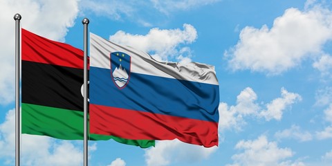 Libya and Slovenia flag waving in the wind against white cloudy blue sky together. Diplomacy concept, international relations.